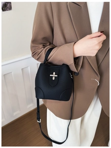 Litchi pattern black bucket bag with silver twist lock shown on a female model