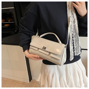 Detail of a creamy white crossbody bag with silver twist lock and flap design