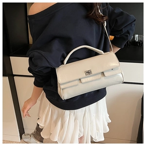 Close-up of cream flap handbag with silver twist lock and adjustable crossbody strap