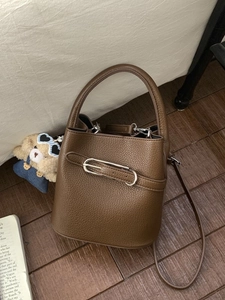 Brown lychee leather bucket bag with silver buckle in a cozy indoor lifestyle setting