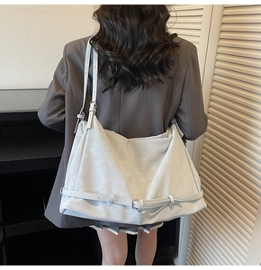 Detail view of large grey tote bag with side buckles shown on a model's shoulder