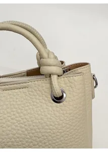Dettaglio della borsa in pelle martellata bianco sporco con morbido manico rotondo