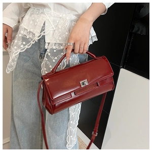 Detail of burgundy glossy leather handbag with silver twist lock and adjustable strap