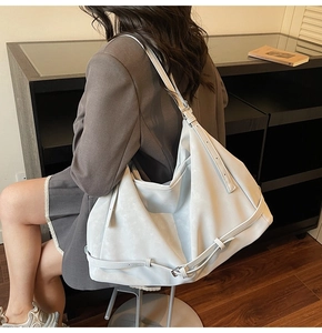 Detail view of large grey-blue leather tote bag with adjustable strap and wrap buckle