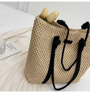 Detail of beige hand-woven tote bag with black rope handles and decorative knots