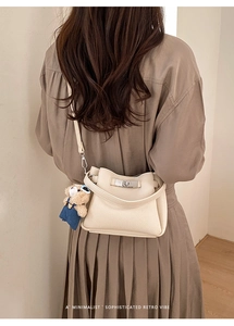 Minimalist cream bucket bag with lychee texture and cute bear charm shown on model