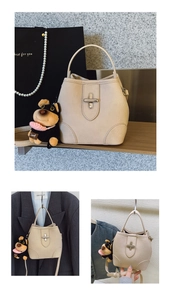 Detail of cream bucket bag with silver twist lock and cute plush dog pendant charm