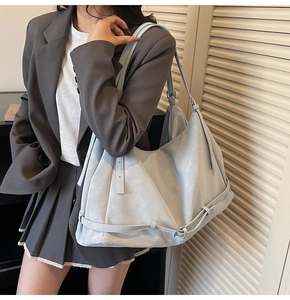 Close-up of light blue large capacity tote bag with decorative strap on a grey suit model