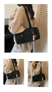 Detail of black matte leather shoulder bag with vintage gold logo and boho beaded charm