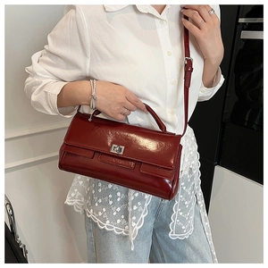 Detail of a dark red glossy flap handbag with a silver turn-lock and adjustable strap