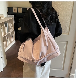 Detail of a large pink suede tote bag with adjustable straps in a chic library setting