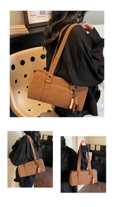Detail of a brown retro underarm bag featuring ethnic wooden and ceramic beaded charms
