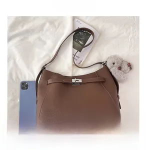 Detail of brown lychee grain leather tote with silver twist lock and plush bunny charm