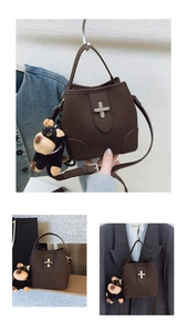 Detail of dark brown lychee leather bucket bag featuring a unique cross metal lock and charm