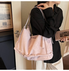 Close-up of a large pale pink tote bag featuring a soft matte texture and metal buckles