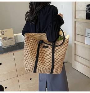 Detail view of woven straw tote bag featuring black rope handles and sturdy hollow texture