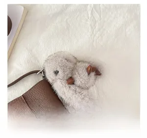 Detailed macro of a soft plush squirrel bag charm attached to a brown lychee leather handbag