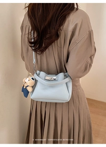 Detail of light blue pebble leather bucket bag with silver clasp and bear charm