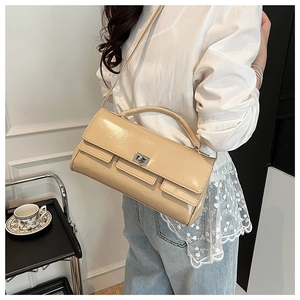 Close-up of beige leather flap handbag with silver twist lock on an elegant model