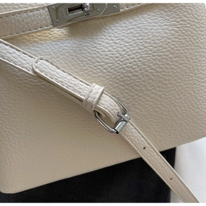 Detail of lychee pattern leather and silver metal twist lock on a beige bucket bag