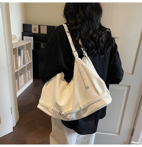 Detailed back view of a white large leather tote bag worn by a model in minimalist room