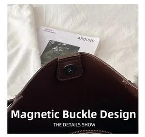 Detail view of the silver magnetic closure on a large brown leather textured bucket bag