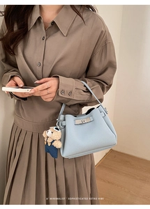 Detail of light blue pebble leather bucket bag with silver twist lock and bear charm