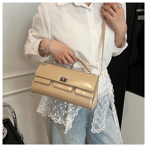 Detail of light beige rectangular flap handbag with silver twist lock on model wearing jeans