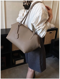 Minimalist tan calfskin leather tote bag shown on shoulder for a stylish commuting look
