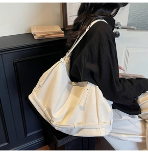 Detail of ivory pleated leather tote bag featuring adjustable buckle straps and soft texture