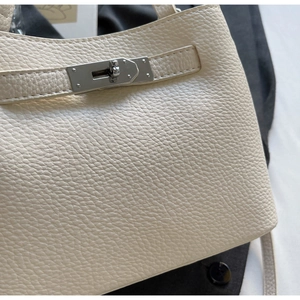 Close-up of cream pebble leather handbag showing silver twist lock and fine stitching