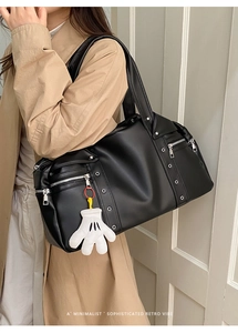 Detail of vintage black biker tote bag with silver studs and chic keychain on female model