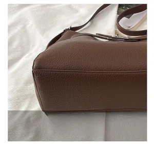 Macro view of brown lychee grain leather handbag with precise stitching details