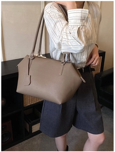 Close-up of a dark khaki pebbled leather tote bag worn on shoulder by a model