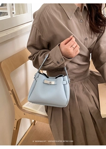 Detail of light blue bucket bag with silver rotating lock and lychee grain leather texture