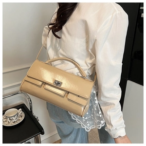 Detail of cream patent leather handbag showing the silver metal twist lock and smooth texture