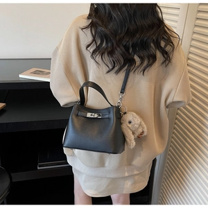 Detailed view of a black lychee-textured bucket bag with metal lock and rabbit charm
