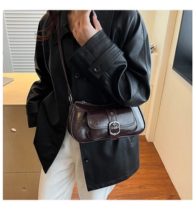 Close-up of a retro dark red underarm bag featuring glossy wrinkled leather and front buckle pouch