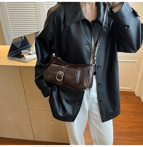 Detail of dark brown glossy crossbody bag with silver buckle in a modern office setting
