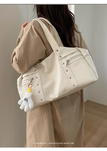Detail of cream retro underarm bag with silver rivets and cartoon glove pendant