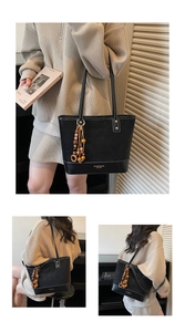 Detail view of black faux leather tote bag with white stitching and wooden bead accessory