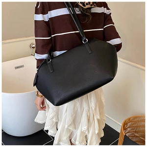 Gros plan du grand sac cabas noir en cuir à motif litchi sur l'épaule d'un modèle