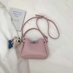 Detail of pink lychee grain leather bucket bag with silver clasp and plush bear charm