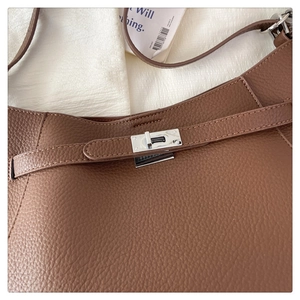 Detailed macro view of brown lychee grain leather bag with silver metallic rotary lock