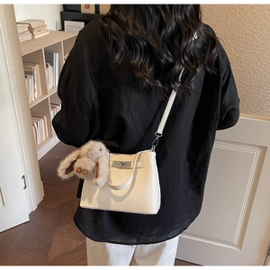 Detail view of white lychee leather bucket bag featuring a silver twist lock and bunny charm