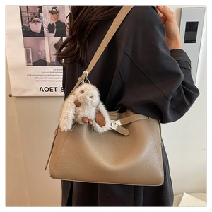Detail view of khaki leather bucket bag with silver turn-lock and plush bunny charm