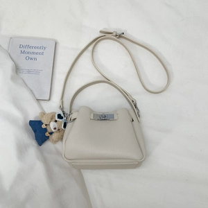 Detail of off-white lychee texture bucket bag with silver lock and cute bear charm