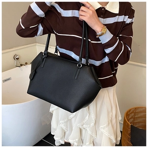 Gros plan sur la texture de cuir noir grainé du sac cabas avec étiquette en cuir assortie