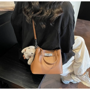 Detail of brown litchi pattern leather bucket bag with silver lock and plush rabbit charm