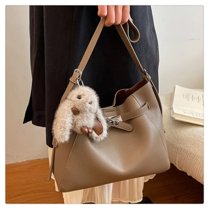 Detail of grey pebble leather shoulder bag with silver clasp and plush rabbit charm